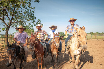 Group of cowboys sitting on horseback on a hot summer day.