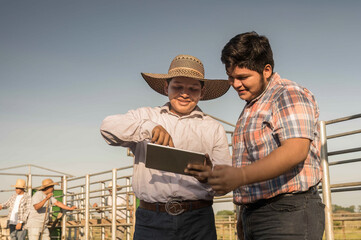 Men with a tablet in their hands on a cattle farm use technology to work.