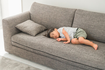 家のソファで寝るアジア人の子供（男の子・熟睡・睡眠・眠る・お昼寝）
