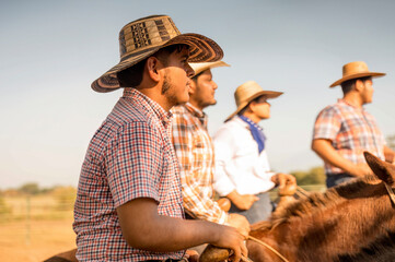 Group of cowboys sitting on horseback on a hot summer day.