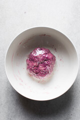 Dry noodles dough wrapped in plastic wrap, pink beet noodles resting, homemade noodles, process of making noodles, dough in white bowl