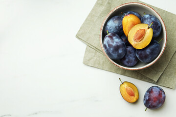 Tasty ripe plums on white marble table, flat lay. Space for text