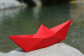 Beautiful red paper boat on stone outdoors, closeup