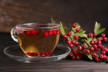 Cup of delicious immunity boosting tea with hawthorn on wooden table, closeup. Space for text