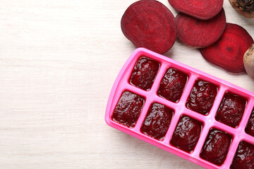 Beet puree in ice cube tray ready for freezing on white wooden table, flat lay. Space for text