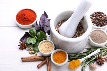 Mortar with pestle and different spices on white wooden table