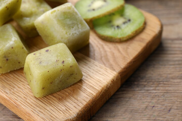 Frozen kiwi puree cubes and ingredient on wooden table, closeup