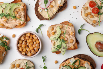 Delicious sandwiches with hummus and different ingredients on white background, flat lay