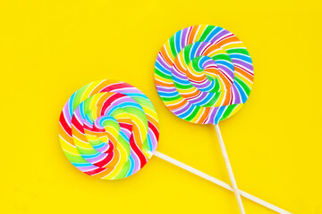 Rainbow lollipop on yellow background.