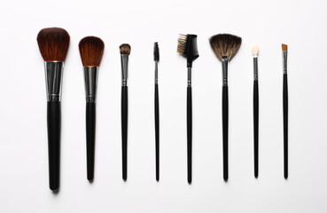 Different makeup brushes on white background, flat lay