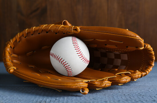 Leather baseball glove with ball on grey wooden table