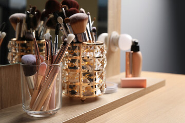 Obraz na płótnie Canvas Set of professional brushes and makeup products near mirror on wooden table, space for text