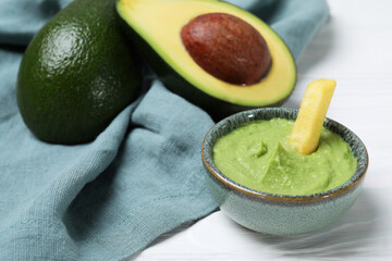 French fry with guacamole dip and avocado served on white wooden table, closeup