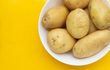 Raw potatoes isolated on yellow background