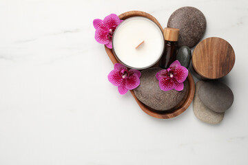 Flat lay composition with spa stones, candle and orchid flowers on white marble table. Space for text