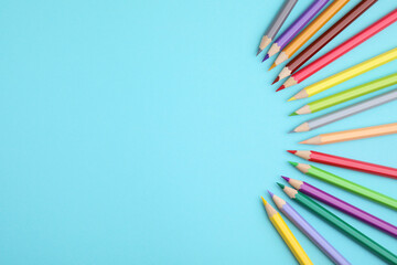 Colorful wooden pencils on light blue background, flat lay. Space for text