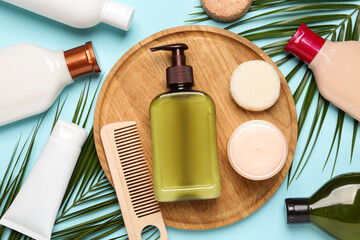 Shampoo bottles, wooden comb, hair and face masks, solid shampoo bars and palm leaves on turquoise background, flat lay