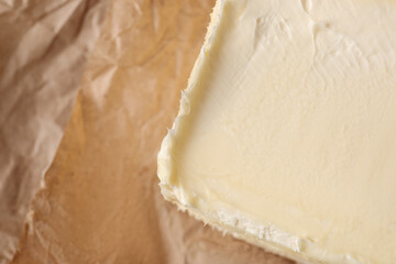 Piece of tasty homemade butter on parchment, closeup. Space for text