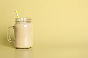 Mason jar of tasty smoothie with straw on beige background. Space for text