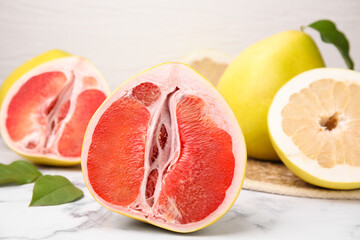 Different tasty pomelo fruits on white marble table, closeup