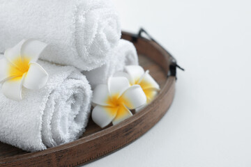 Tray with rolled bath towels on white table, closeup. Space for text