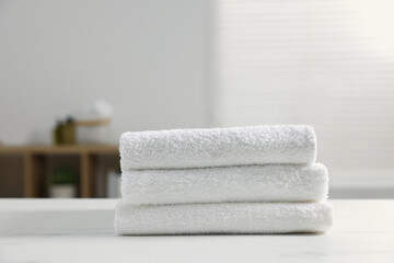 Obraz na płótnie Canvas Stacked bath towels on white table indoors