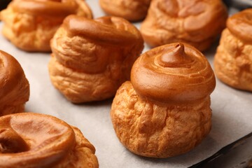 Delicious fresh profiteroles on baking pan, closeup