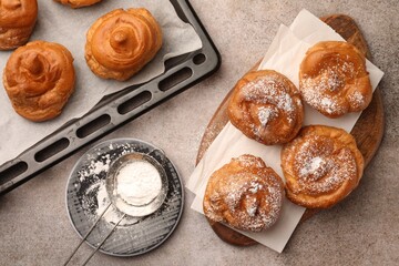 Delicious profiteroles with powdered sugar on grey table, flat lay