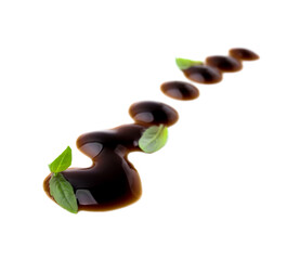 Balsamic glaze and basil leaves on white background