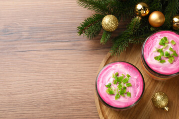 Glass jars of herring under fur coat and Christmas decor on wooden table, flat lay with space for text. Traditional Russian salad