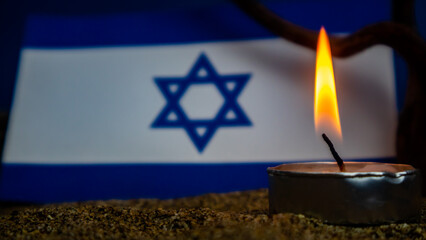 Israeli flag and candles burning in front of it, Holocaust memory day