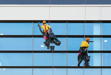 Two workers washing windows of the modern building - 556847081