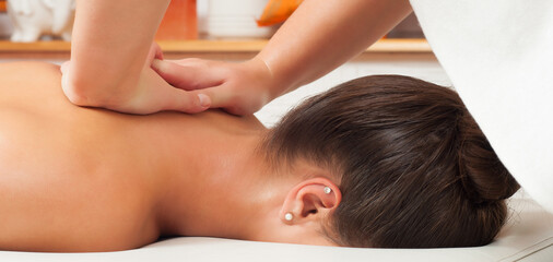 Obraz na płótnie Canvas Girl getting back massage in massage salon, health spa from a woman massage therapist 