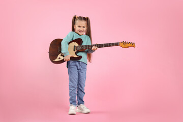 Happy girl with electric guitar on pink background. Space for text