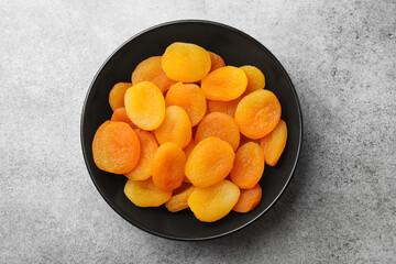 Plate of tasty apricots on grey table, top view. Dried fruits
