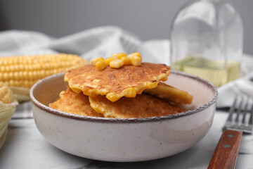 Tasty corn pancakes in bowl on table, closeup
