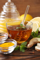Tea with honey and ingredients on wooden table