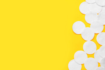 Soft clean cotton pads on yellow background, flat lay. Space for text