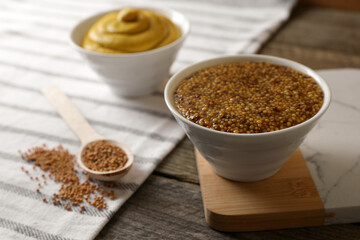 Bowl of whole grain mustard on wooden table, closeup. Space for text