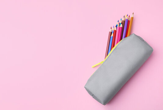 Many colorful pencils in pencil case on pink background, top view. Space for text