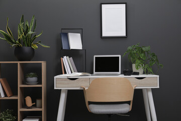 Workplace with laptop, stationery on desk and chair in home office