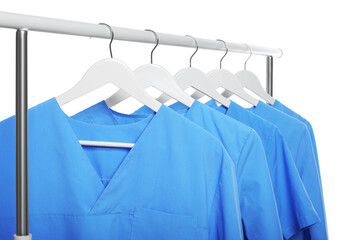 Light blue medical uniforms on rack against white background - obrazy, fototapety, plakaty