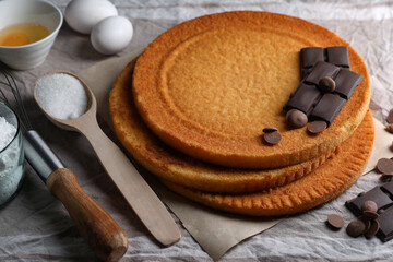 Delicious homemade sponge cakes and ingredients on grey tablecloth, closeup