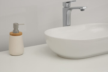 White washbasin and soap dispenser in bathroom. Interior design