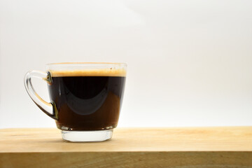 glass of black coffee put on wooden cutting board
