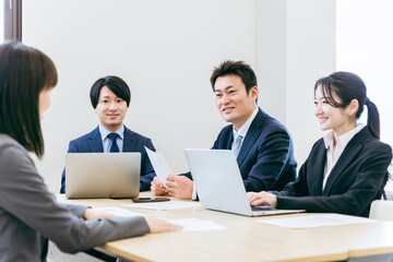 会社の会議室で会議・打ち合わせ・ミーティングするビジネスマンとビジネスウーマン（男女・アジア人）
