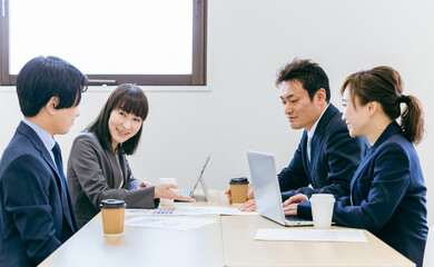 会社の会議室で会議・打ち合わせ・ミーティングするビジネスマンとビジネスウーマン（男女・アジア人）
