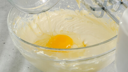 Cream cheese, eggs, and sugar in a bowl. Cheesecake recipe, mixing ingredients in a glass bowl