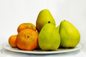 several tangerines and several pears on a white plate