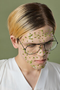 High angle view close-up portrait of queer model with green flowers on face wearing glasses